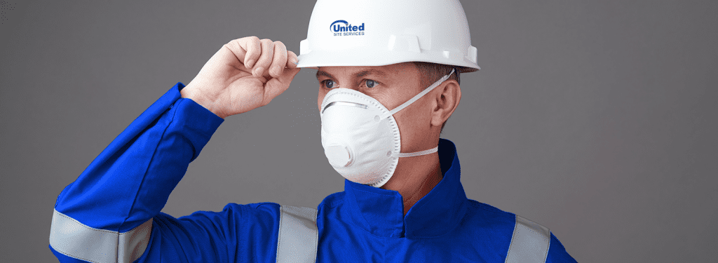 Worker in blue uniform and white helmet wearing an n95 mask