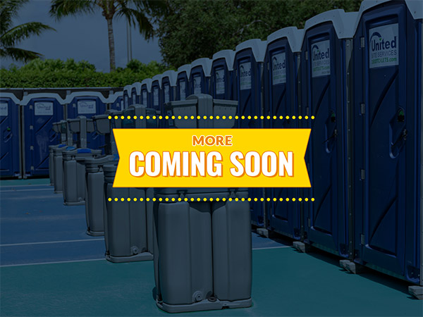 "more coming soon" sign with porta potties and hand washing stations in the background