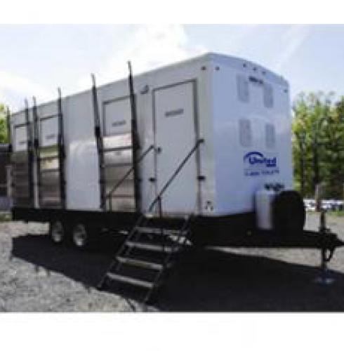 A mobile shower trailer exterior with multiple stalls parked outdoors, featuring stairs leading to the entrance doors, under a clear sky