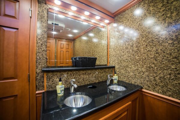 Luxurious restroom trailer with gleaming marble walls and countertop, featuring twin sinks