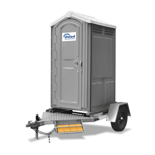 A portable restroom mounted on a small towable trailer, featuring a ramp for accessibility