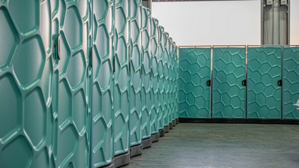 A row of teal green Hydroflow showers with honeycomb design, lined up in a warehouse