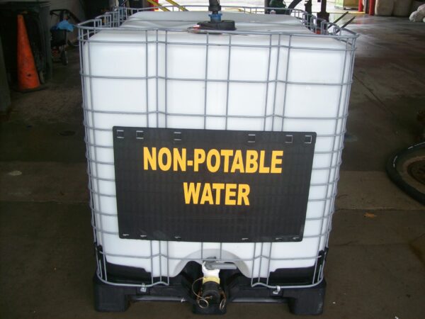 A large white container with a black and yellow sign reading "non-potable water" attached to the front, located in an industrial setting